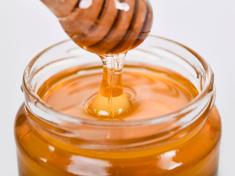 Versement du miel de thym doré dans un bocal en verre